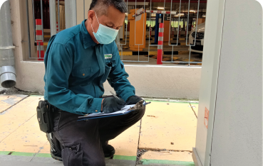 A man is writing something on a clipboard during pest control inspection in Kuala Lumpur.
