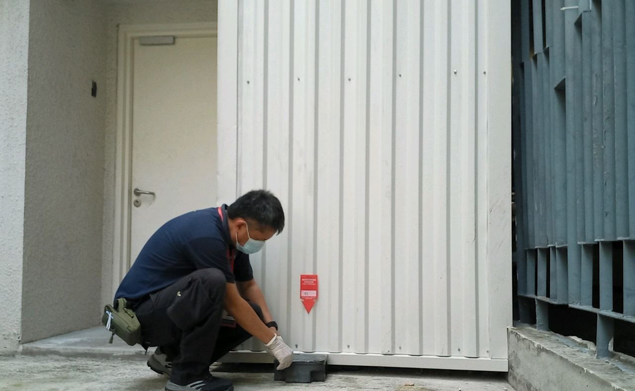 A blue shirt man is installing a trap during rat and rodent pest control service.