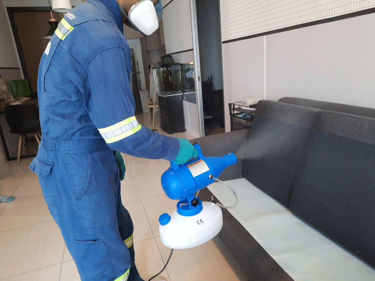 A man with blue uniform is spraying pesticide for bed bug pest control.