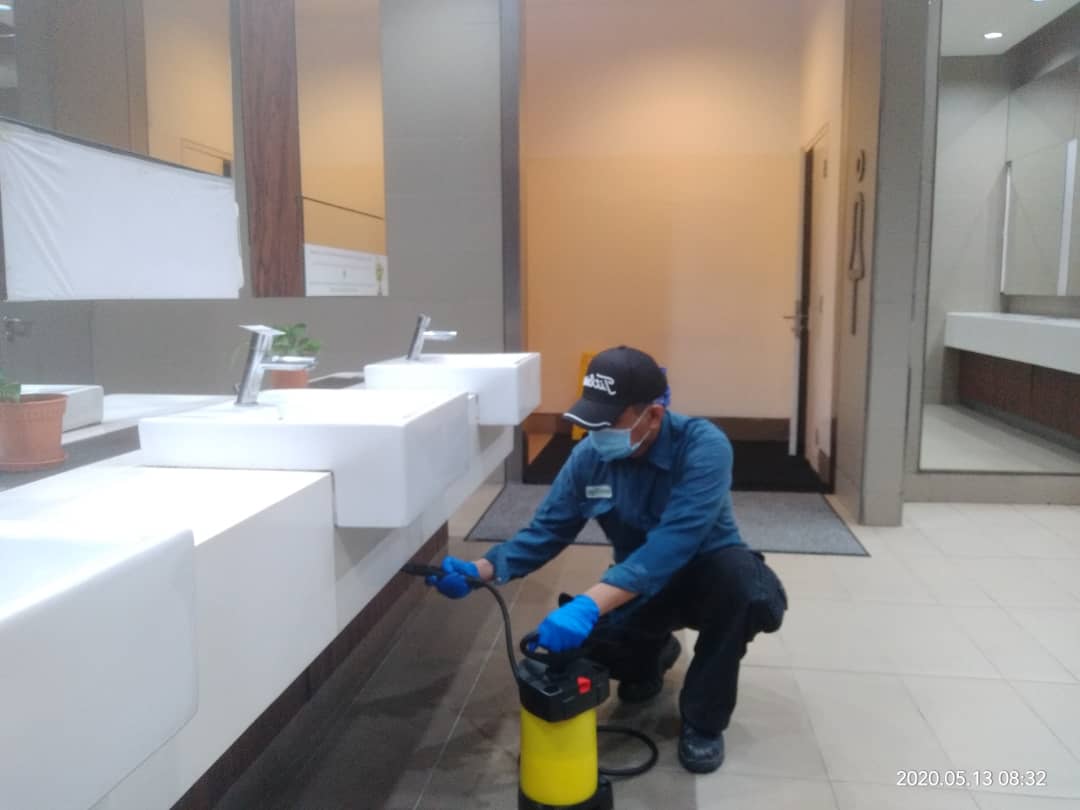 A staff is spraying pesticide under the sink during cockroach pest control service in Malaysia.